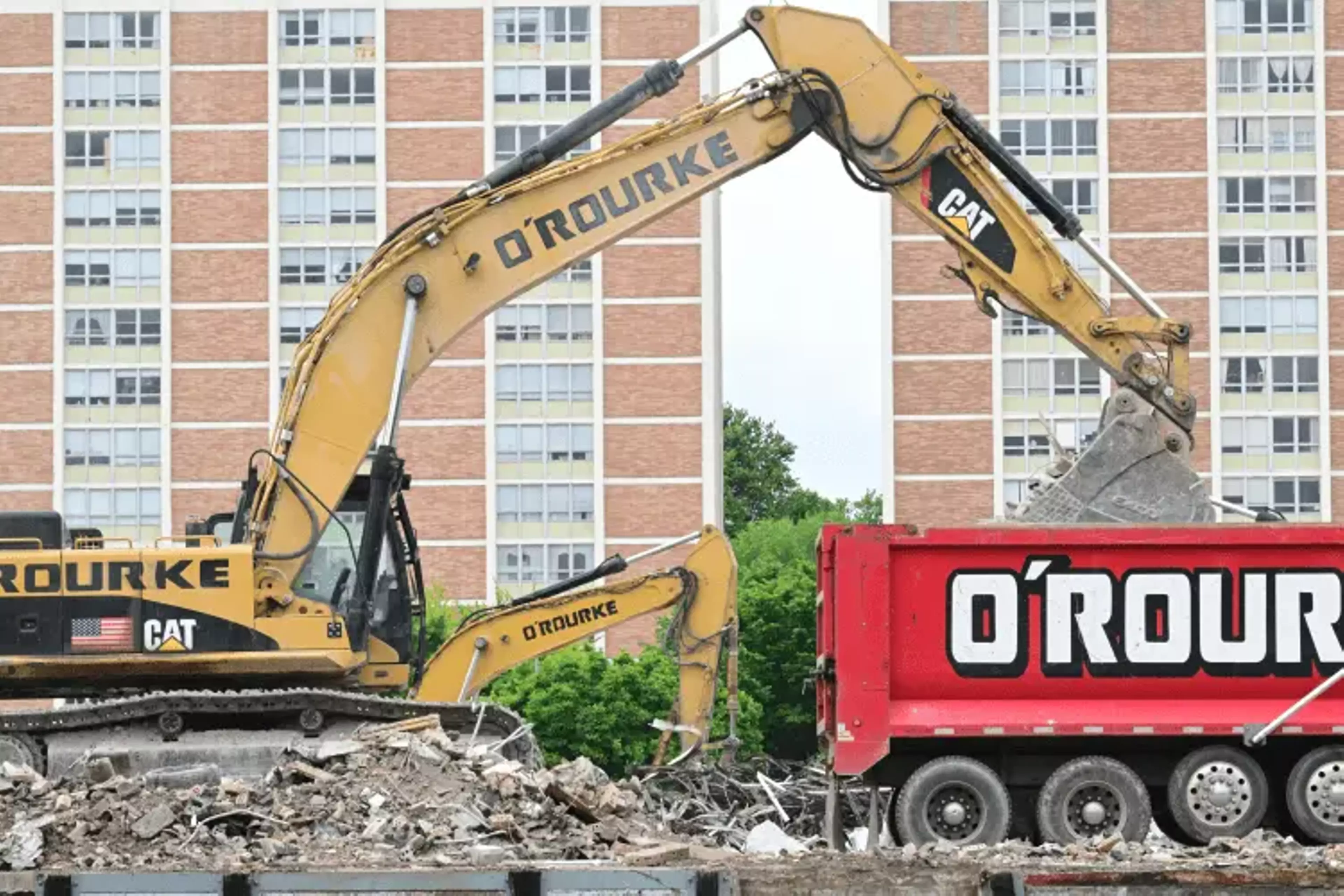 Construction vehicles picking up remains of a demolition job.